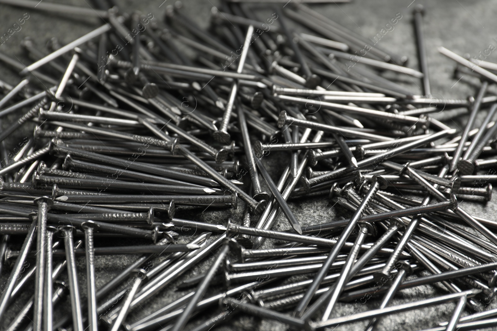 Photo of Many metal nails on grey table, closeup