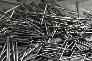 Photo of Many metal nails on grey table, closeup