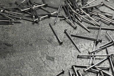 Photo of Many metal nails on grey table, closeup. Space for text