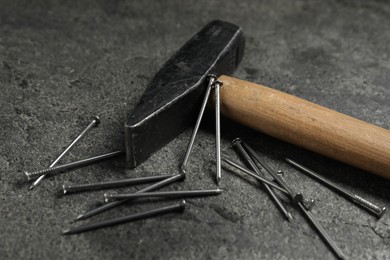 Photo of Hammer and metal nails on grey table, closeup