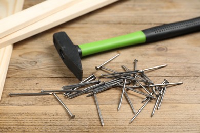 Photo of Hammer, metal nails and planks on wooden table, closeup