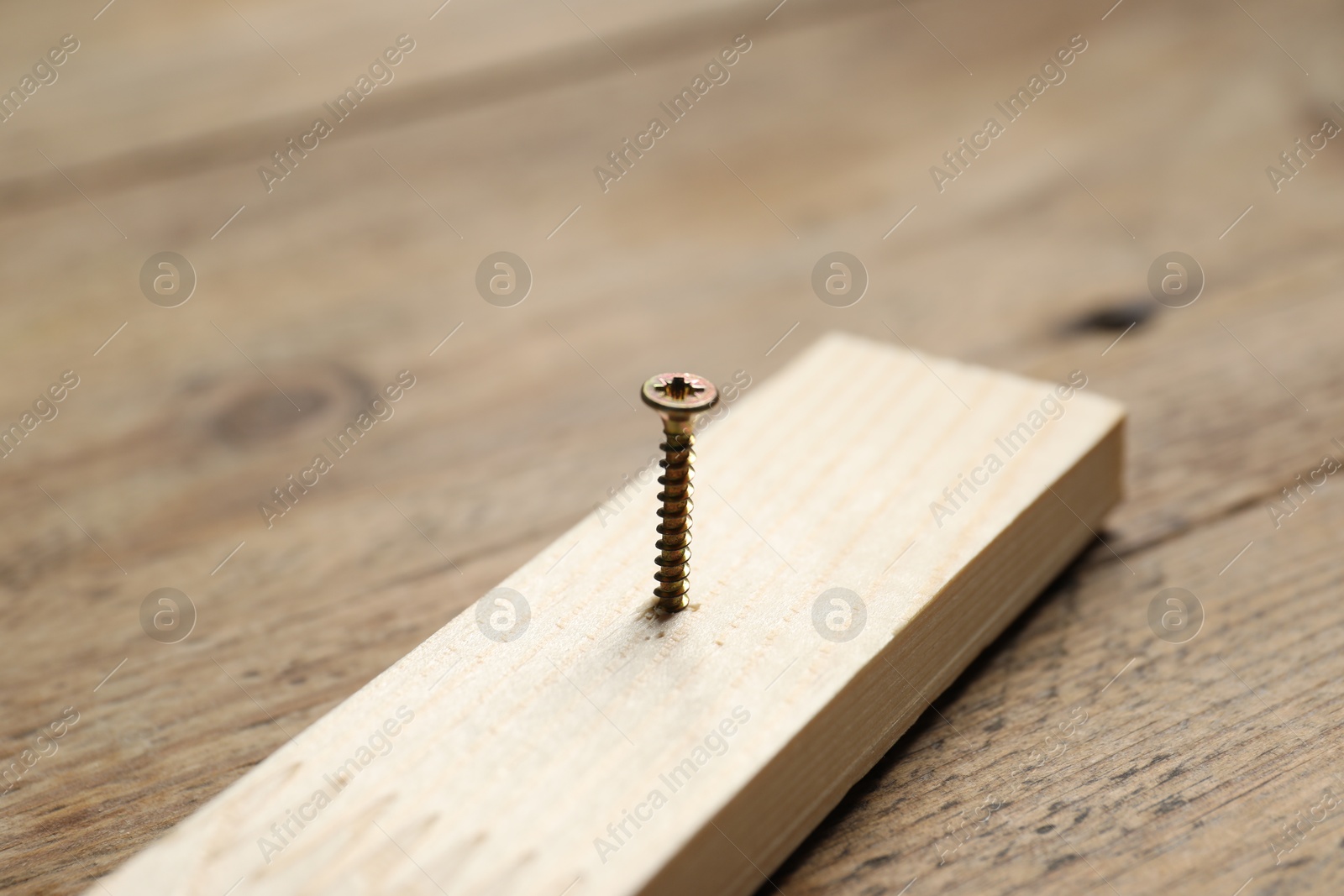 Photo of Metal nail in plank on wooden table, closeup