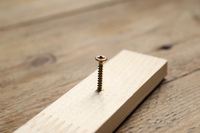 Photo of Metal nail in plank on wooden table, closeup