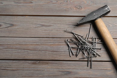 Photo of Hammer and metal nails on wooden table, flat lay. Space for text