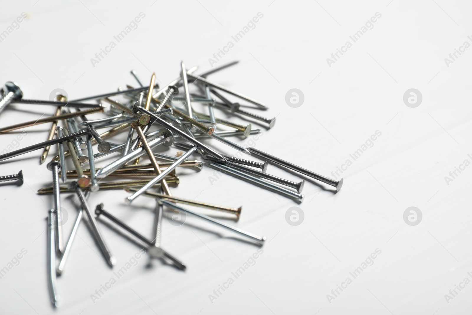 Different metal nails on white wooden table, closeup. Space for text Photo of Different metal nails on white wooden table, closeup. Space for text