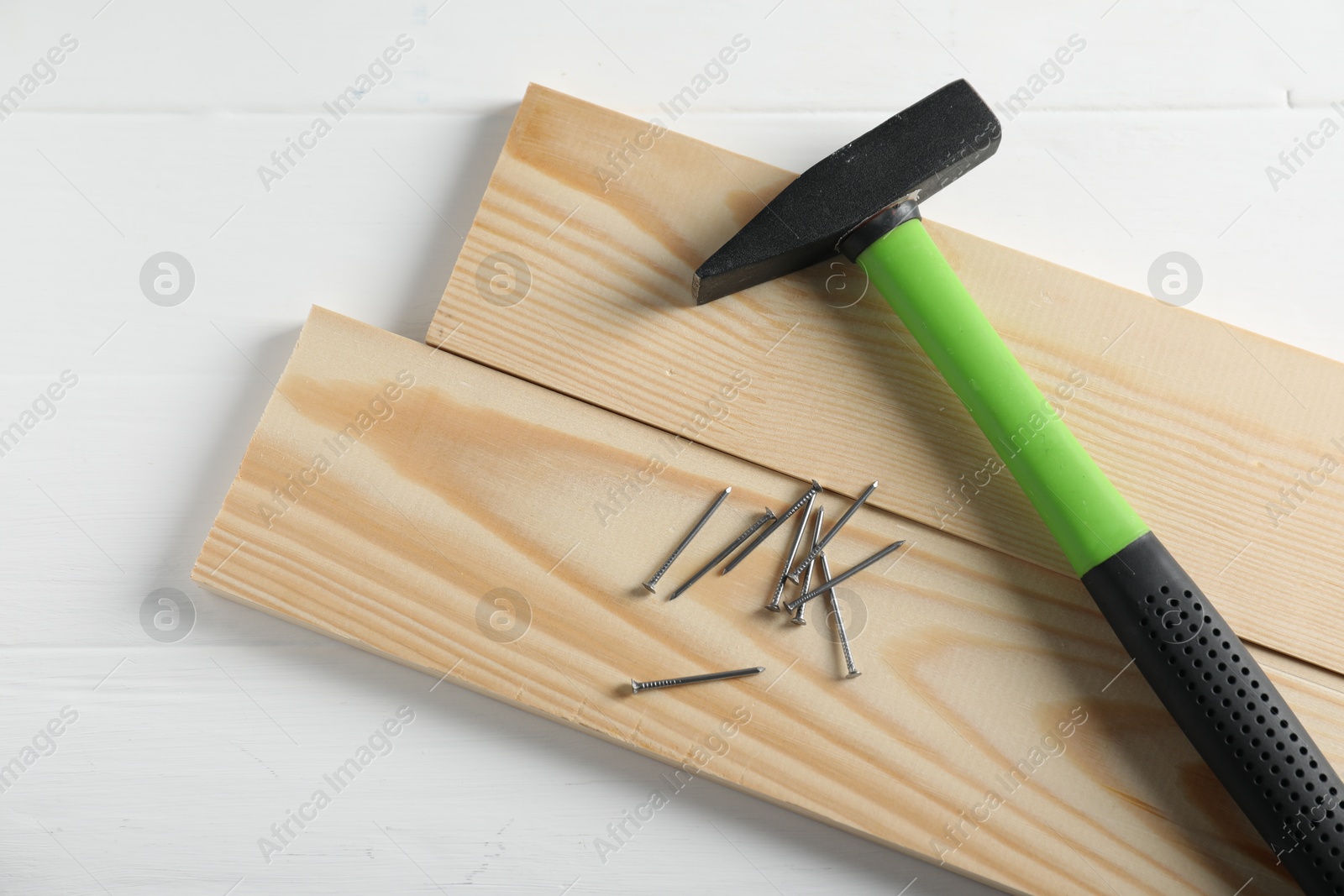 Hammer, metal nails and wooden planks on white table, flat lay Photo of Hammer, metal nails and wooden planks on white table, flat lay