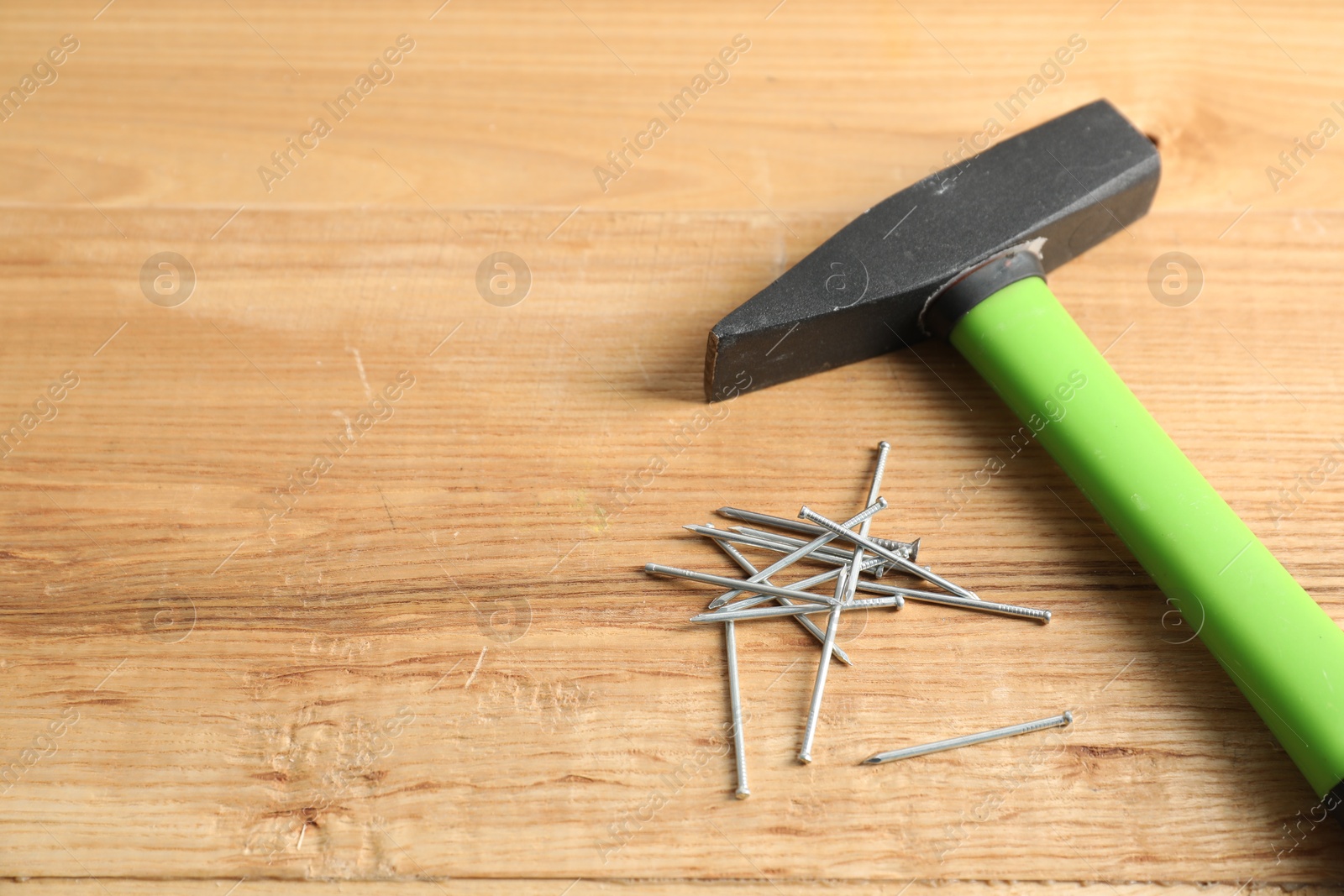 Metal nails and hammer on wooden table, closeup. Space for text Photo of Metal nails and hammer on wooden table, closeup. Space for text