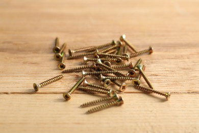 Photo of Many metal screws on wooden table, closeup