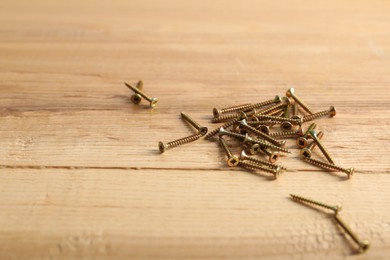 Photo of Many metal screws on wooden table, closeup. Space for text