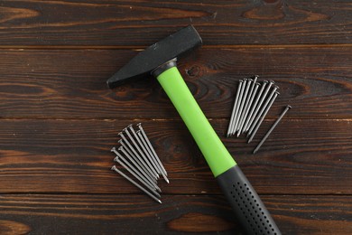 Photo of Metal nails and hammer on wooden table, flat lay