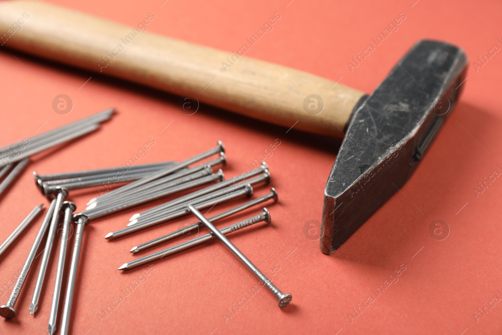 Metal nails and hammer on coral background, closeup Photo of Metal nails and hammer on coral background, closeup