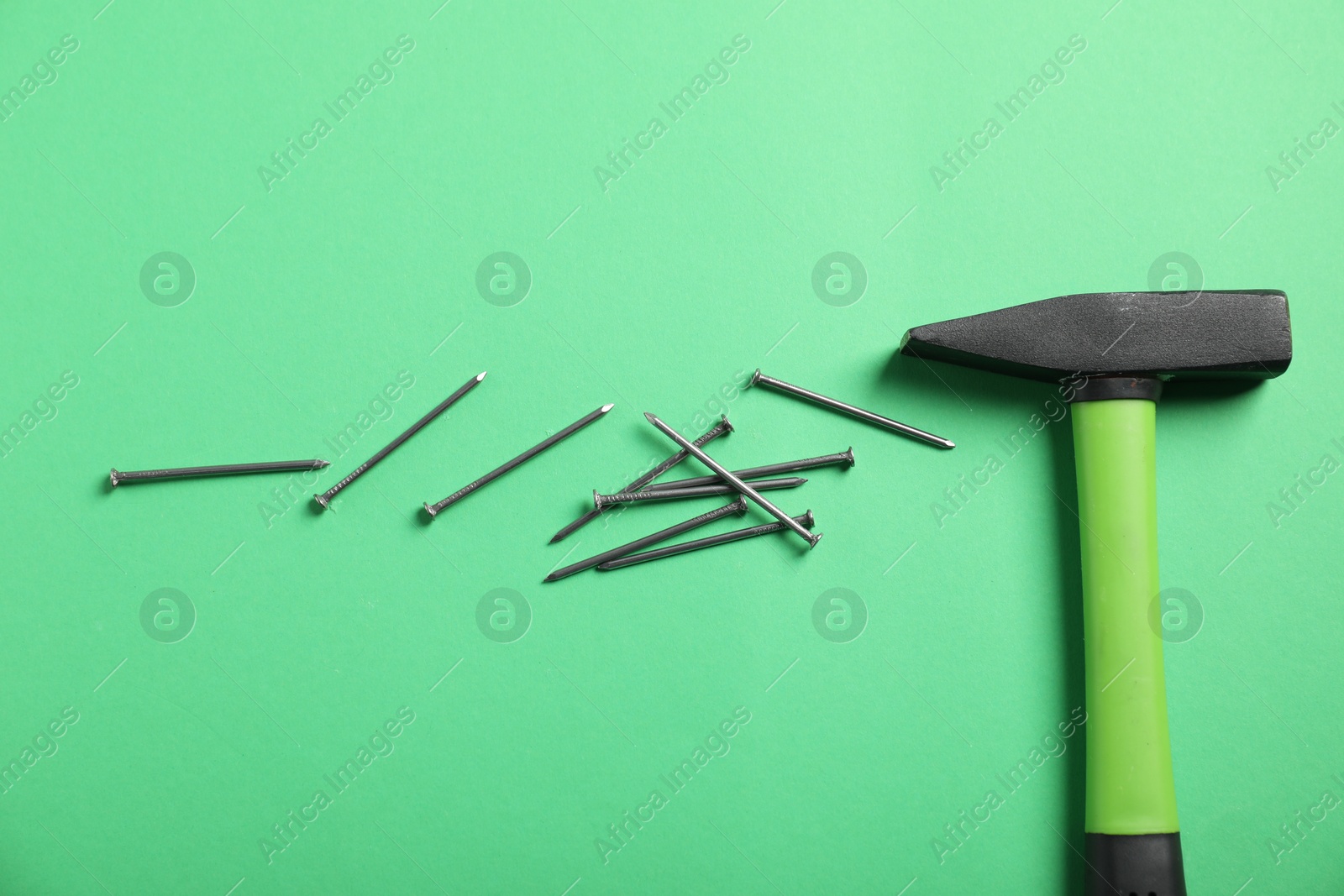 Metal nails and hammer on green background, flat lay Photo of Metal nails and hammer on green background, flat lay