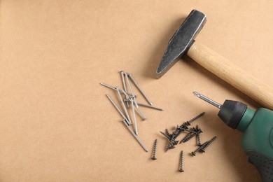 Photo of Metal nails, screws, hammer and electric screwdriver on cardboard surface, above view. Space for text