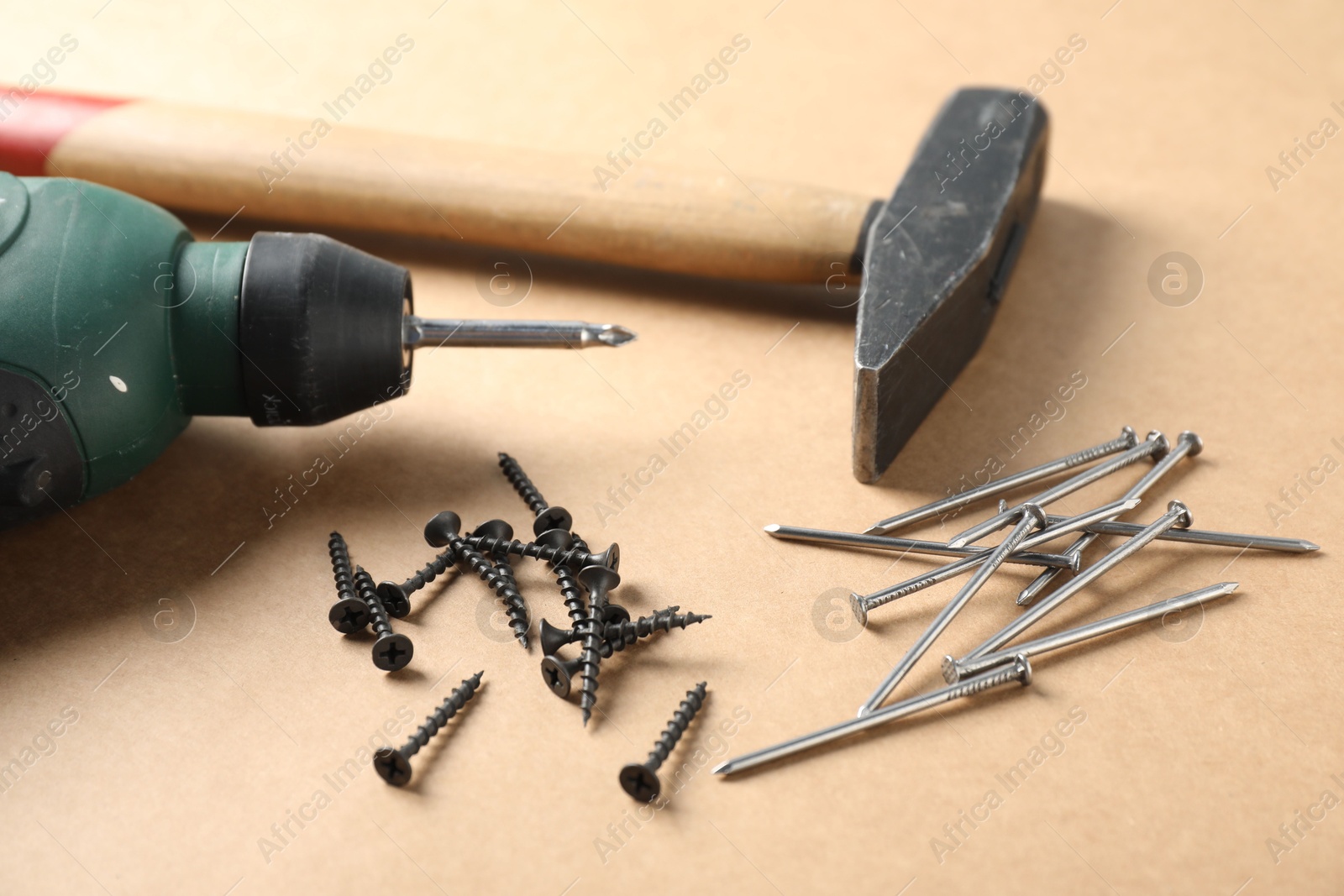 Metal nails, screws, hammer and electric screwdriver on cardboard surface, closeup Photo of Metal nails, screws, hammer and electric screwdriver on cardboard surface, closeup