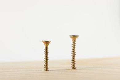 Photo of Metal screws in wooden plank on white background, closeup