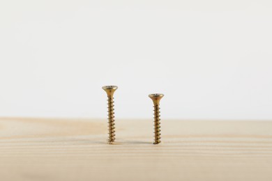 Photo of Metal screws in wooden plank on white background, closeup