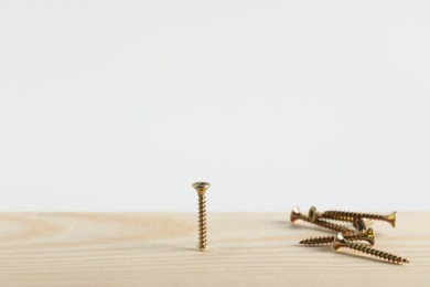 Photo of Metal screws and wooden plank on white background, closeup. Space for text