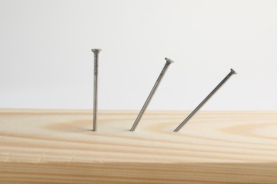 Photo of Metal nails in wooden plank on white background, closeup