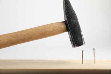 Photo of Hammering nail into wooden plank on white background, closeup