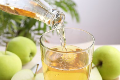Photo of Pouring fresh cider into glass at table, closeup