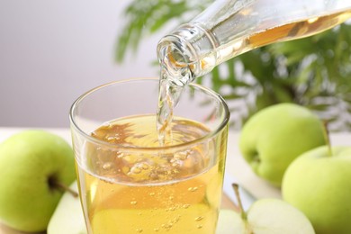 Photo of Pouring fresh cider into glass at table, closeup