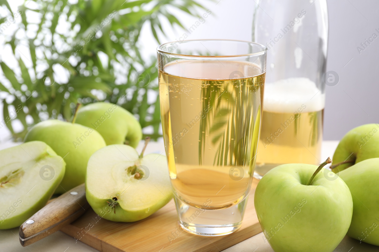 Photo of Fresh cider in glass, bottle, apples and knife on table, closeup
