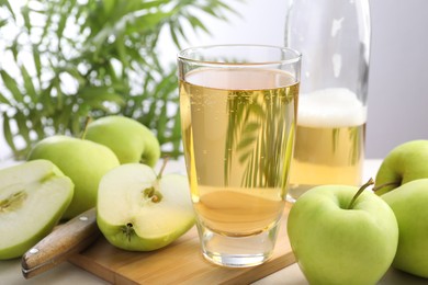 Photo of Fresh cider in glass, bottle, apples and knife on table, closeup