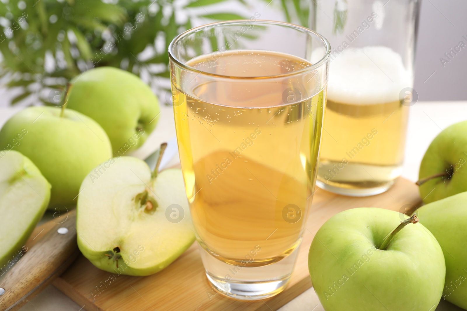 Photo of Fresh cider in glass, bottle, apples and knife on table, closeup