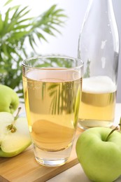 Photo of Fresh cider in glass, bottle and apples on table, closeup