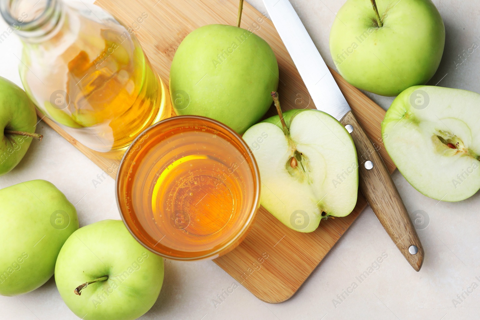 Photo of Fresh cider in glass, bottle, apples and knife on beige table, flat lay