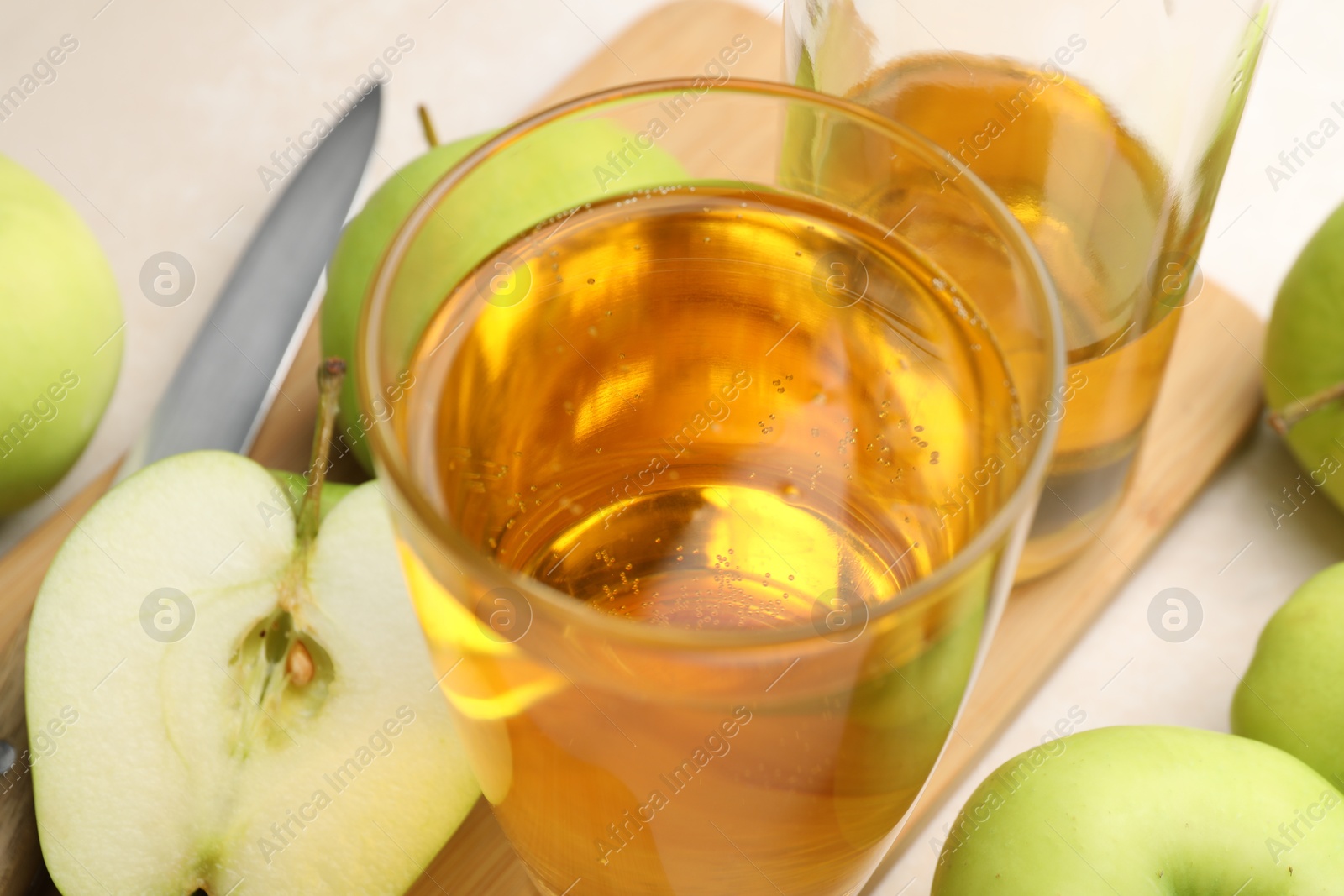 Photo of Fresh cider in glass, bottle, apples and knife on table, closeup