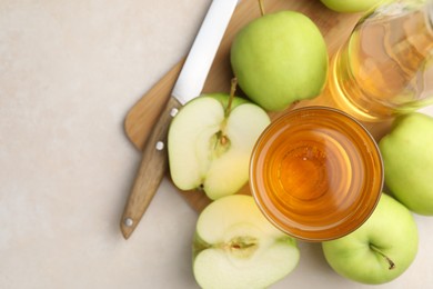 Photo of Fresh cider in glass, bottle, apples and knife on beige table, top view. Space for text