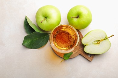 Photo of Fresh cider in glass and apples on beige table, flat lay