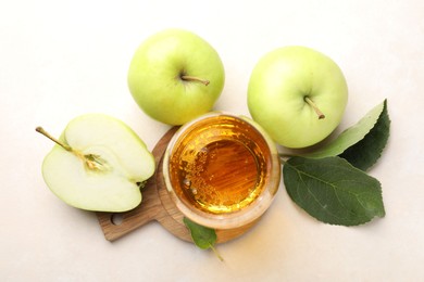Photo of Fresh cider in glass and apples on beige table, flat lay