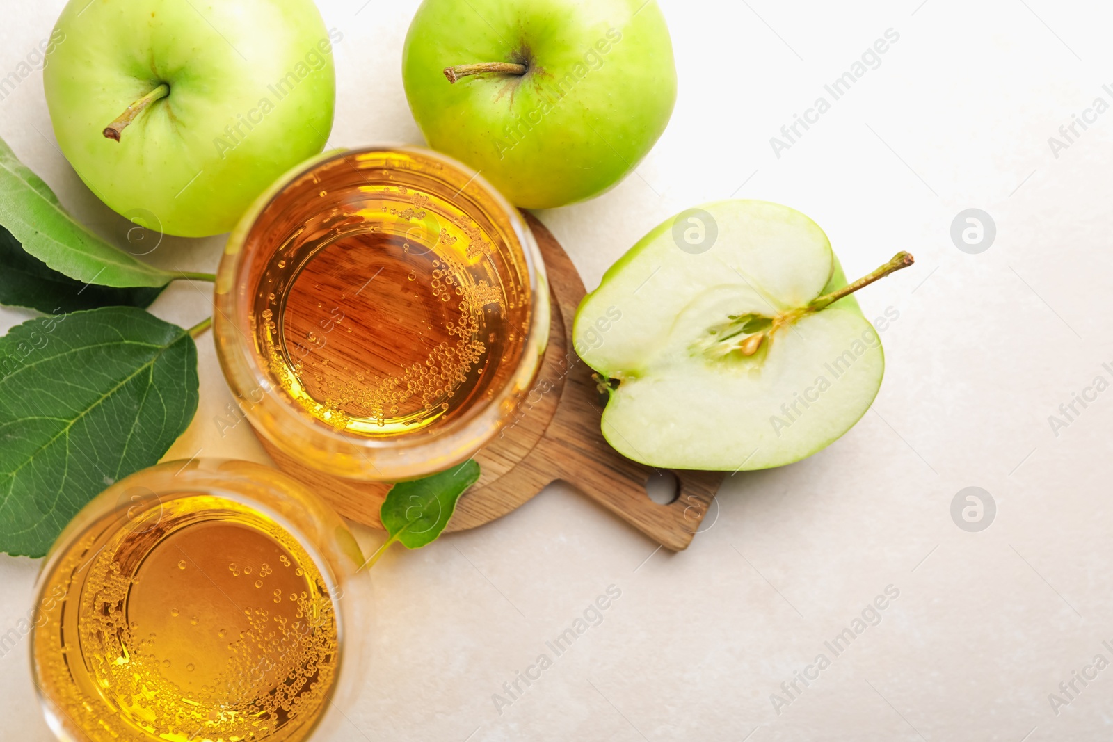 Fresh cider in glass and apples on beige table, flat lay Photo of Fresh cider in glass and apples on beige table, flat lay