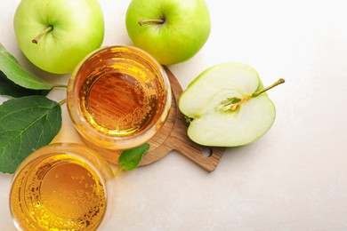 Photo of Fresh cider in glass and apples on beige table, flat lay