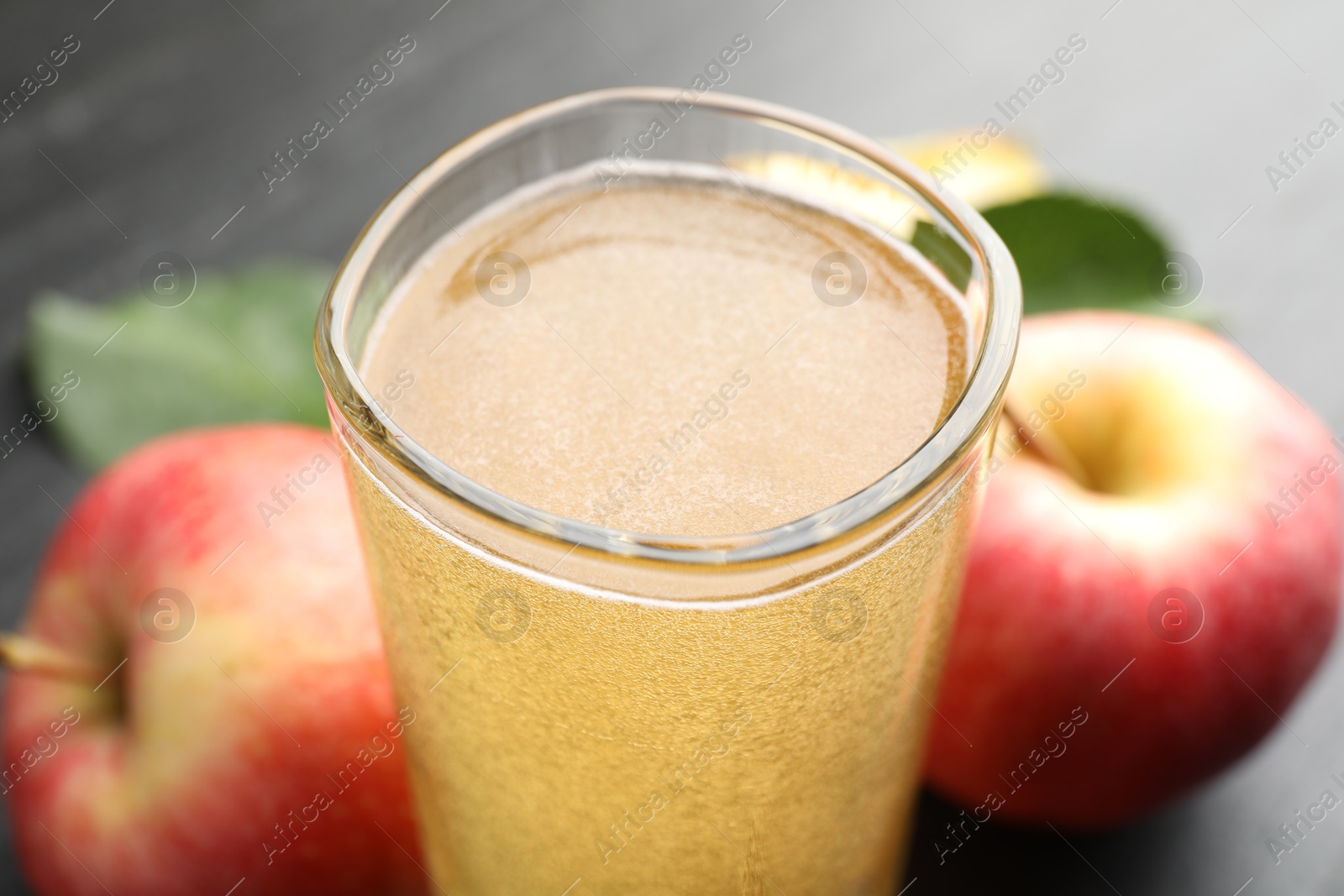 Fresh cider in glass and apples on black table, closeup Photo of Fresh cider in glass and apples on black table, closeup