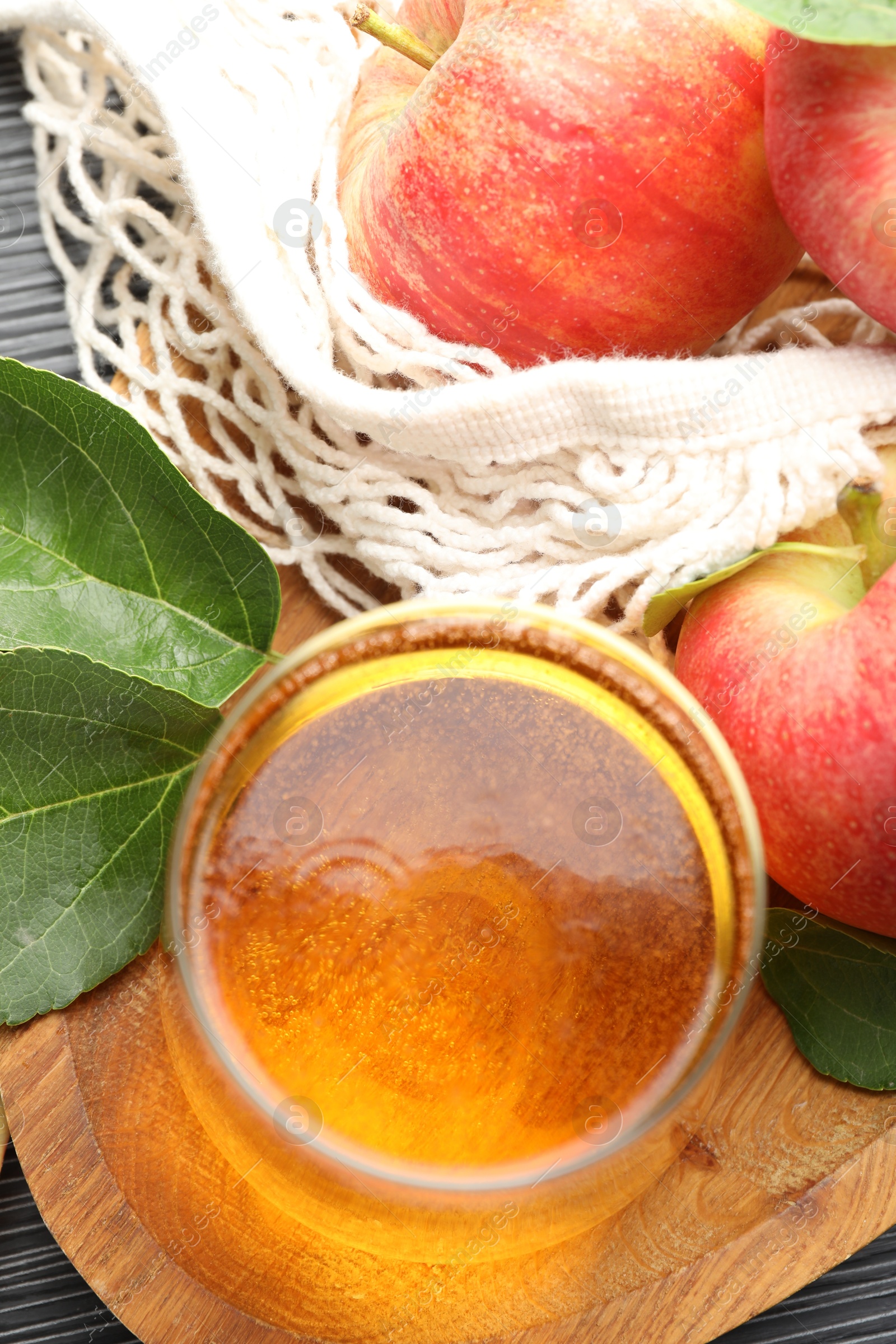 Fresh cider in glass, apples and green leaves on table, flat lay Photo of Fresh cider in glass, apples and green leaves on table, flat lay