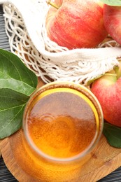 Photo of Fresh cider in glass, apples and green leaves on table, flat lay