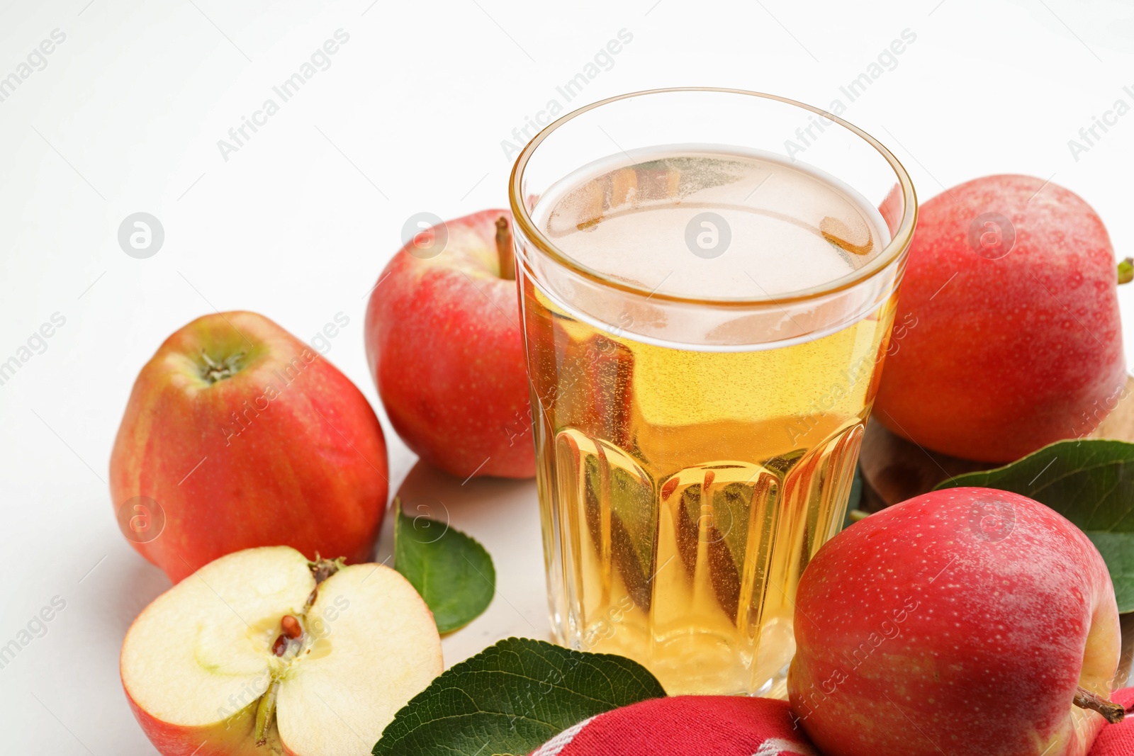 Fresh cider in glass and apples on white table, closeup Photo of Fresh cider in glass and apples on white table, closeup