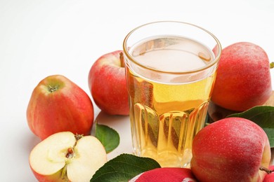 Photo of Fresh cider in glass and apples on white table, closeup