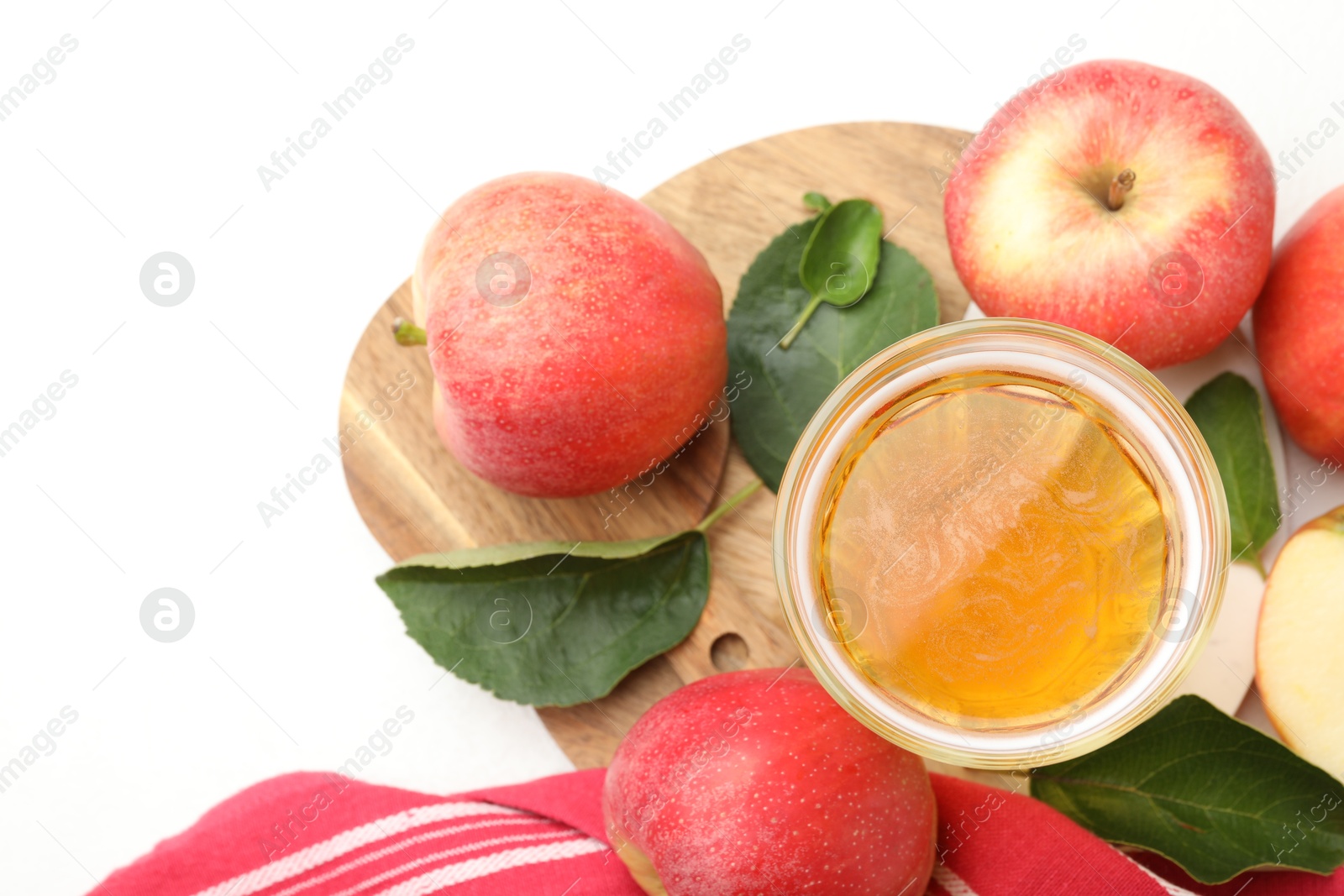 Fresh cider in glass, apples and green leaves on white table, flat lay Photo of Fresh cider in glass, apples and green leaves on white table, flat lay