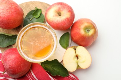 Photo of Fresh cider in glass, apples and green leaves on white table, flat lay
