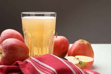 Photo of Fresh cider in glass and apples on white table, closeup