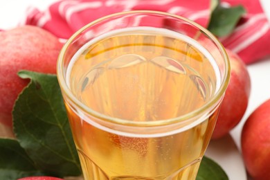 Photo of Fresh cider in glass and apples on table, closeup