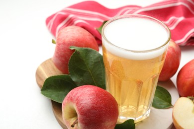 Photo of Fresh cider in glass and apples on white table, closeup