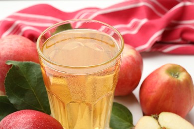 Photo of Fresh cider in glass and apples on table, closeup
