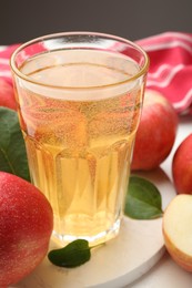 Photo of Fresh cider in glass and apples on table, closeup