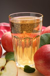 Photo of Fresh cider in glass and apples on table, closeup