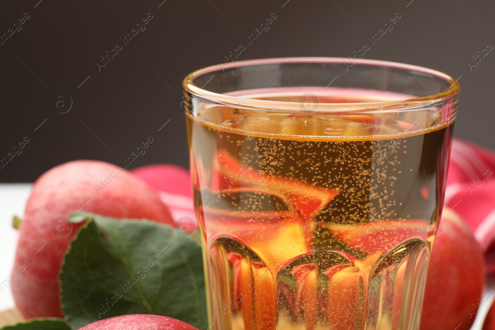 Fresh cider in glass and apples on table, closeup Photo of Fresh cider in glass and apples on table, closeup